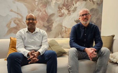 Moayed Hamza and Mark O'Neill sitting on a couch posing for a photo.